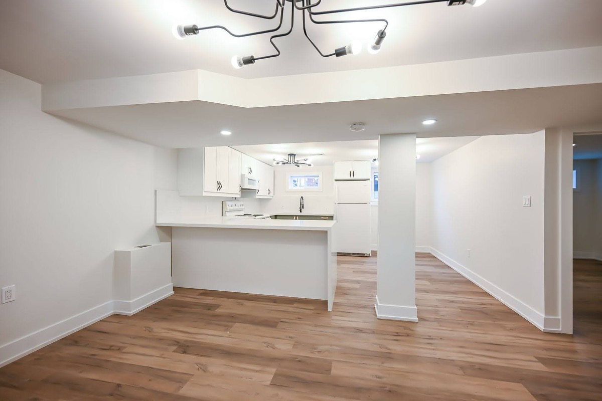 Clean finished basement with modern fixtures and warm wood flooring — strong portfolio shot showing complete transformation — Winchester, Hamilton | MTC Renovations