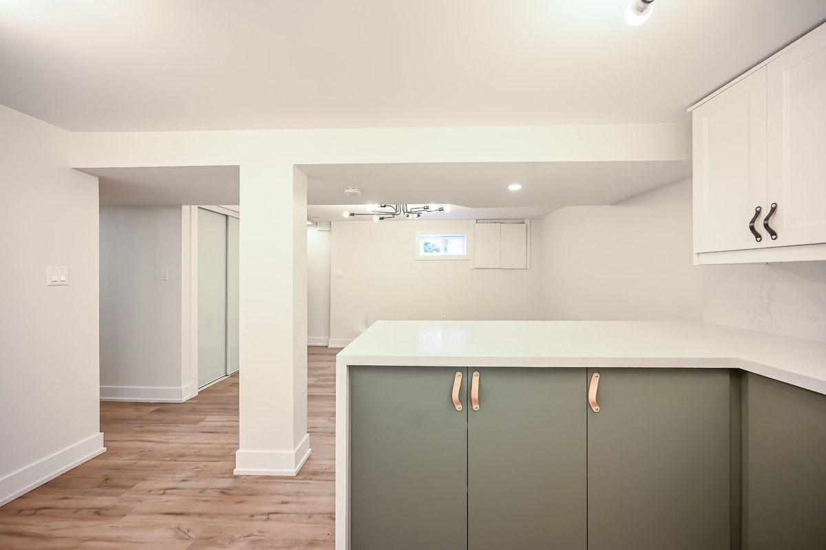 Bright finished basement with sage green cabinets and white quartz — premium wide-angle portfolio shot perfect for virtual tours — Winchester, Hamilton | MTC Renovations