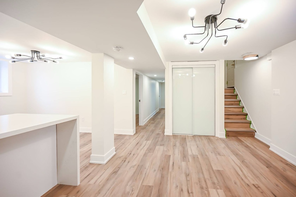 Bright finished basement with modern fixtures and warm wood flooring — excellent wide-angle portfolio shot — Winchester, Hamilton | MTC Renovations