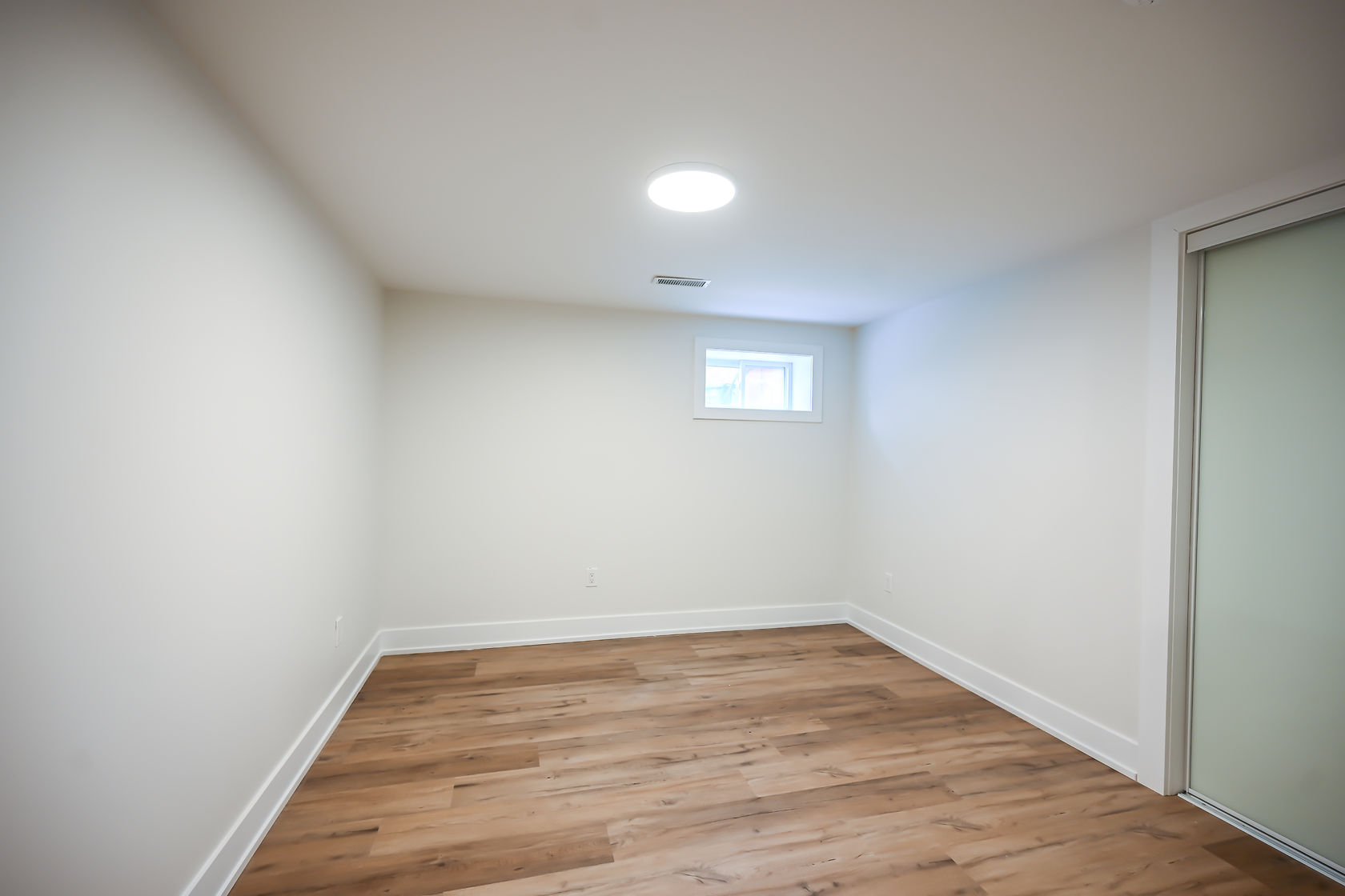 Clean finished basement with quality hardwood flooring and professional lighting — excellent virtual tour shot with strong marketing versatility — Winchester, Hamilton | MTC Renovations
