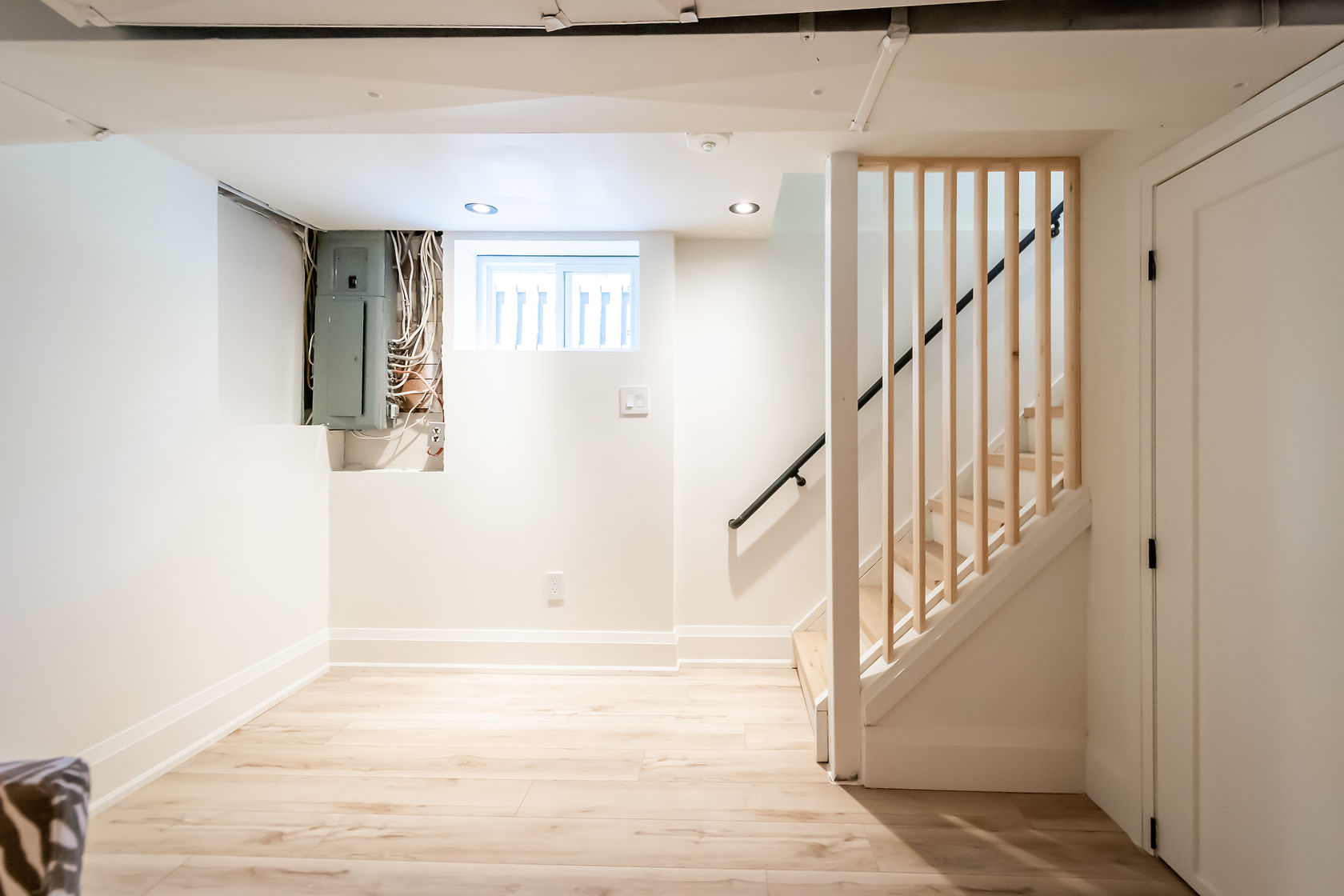 Clean finished basement with warm wood flooring and modern staircase — excellent portfolio shot showing complete transformation — Rosedene, Hamilton | MTC Renovations
